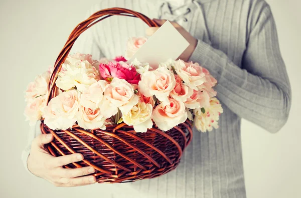 Hombre sosteniendo cesta llena de flores y postal — Foto de Stock