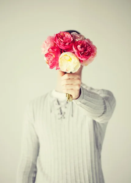 Man die betrekking hebben op zijn gezicht met boeket van bloemen — Stockfoto