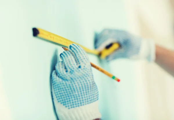 Gros plan du mâle dans des gants mesurant le mur avec du ruban adhésif — Photo