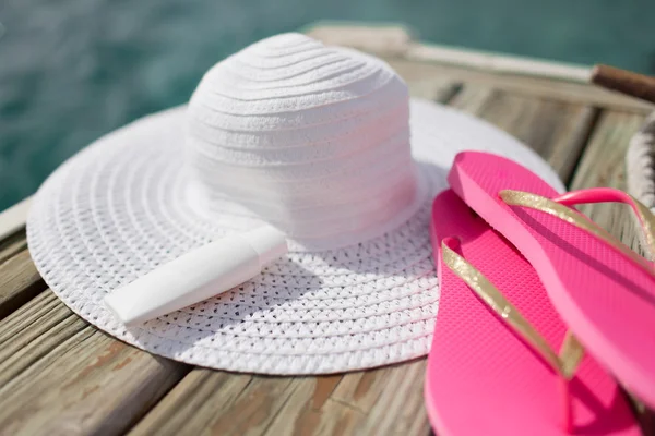 Close up van hoed, zonnebrandcrème en slippers aan zee — Stockfoto