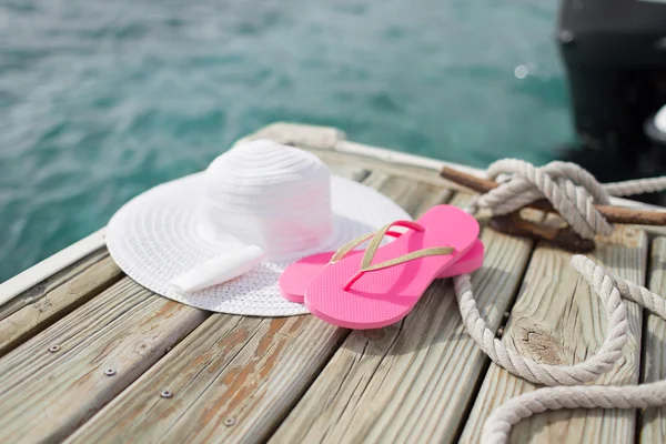 Close up of hat, sunscreen and slippers at seaside — Stock Photo, Image