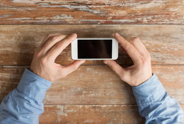 Close up of male hands with smartphone on table — Stock Photo, Image