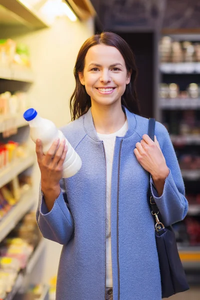 Ευτυχισμένη γυναίκα, κρατώντας το μπουκάλι γάλα στην αγορά — Φωτογραφία Αρχείου