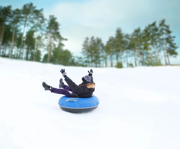 Heureux jeune homme glissant vers le bas sur la neige tube — Photo