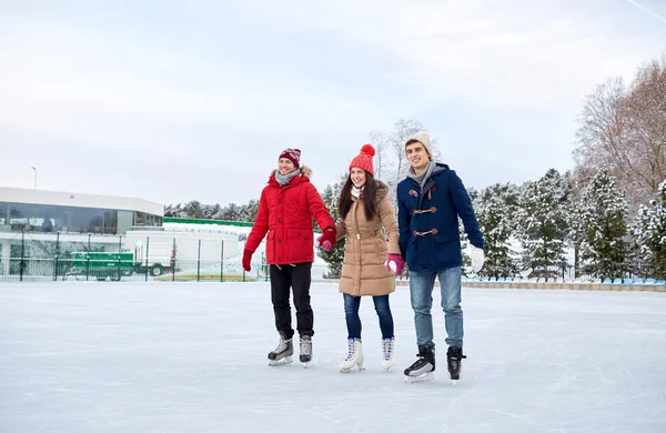 Amigos felizes patinação no gelo no ringue ao ar livre — Fotografia de Stock