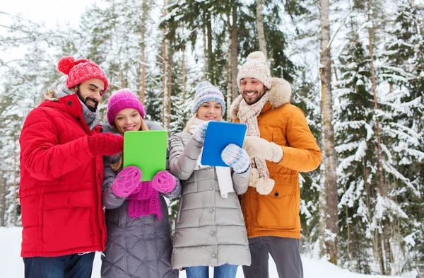 Smiling friends with tablet pc in winter forest — Stock Photo, Image