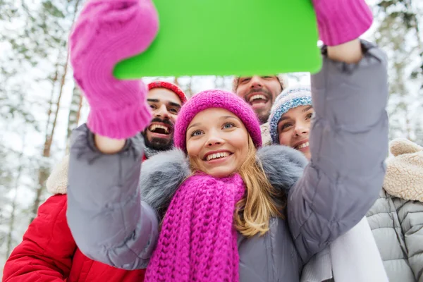 Lachende vrienden met tablet pc in winter forest — Stockfoto