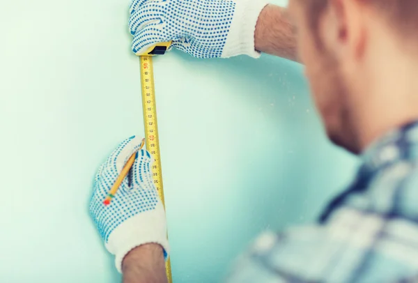 Closeup of male in gloves measuring wall with tape — Stock Photo, Image