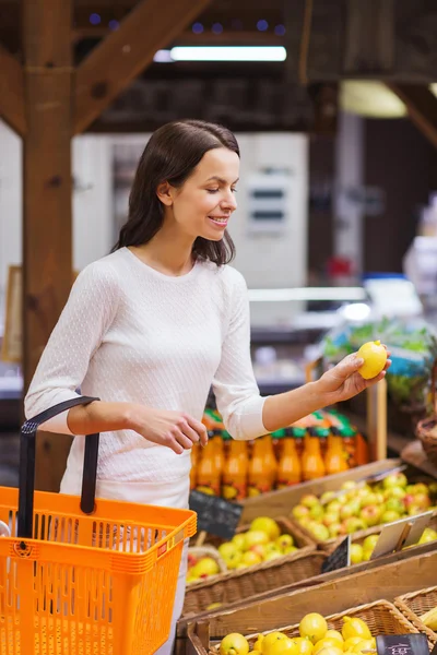 Gelukkig jonge vrouw met levensmiddelen mand in markt — Stockfoto