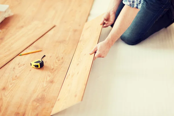 Primo piano di mani maschili intalling pavimento in legno — Foto Stock