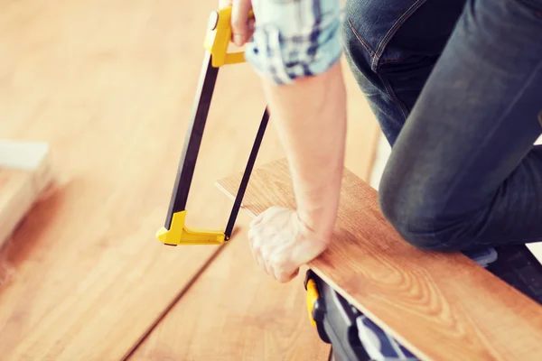 Close up de mãos masculinas corte de placa de piso de parquet — Fotografia de Stock