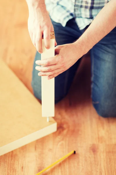 Primo piano di mani maschili assemblaggio gambe a tavola — Foto Stock