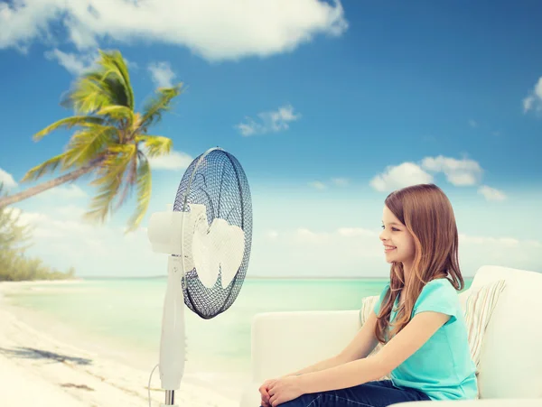 Усміхнена маленька дівчинка з великим вентилятором вдома — стокове фото