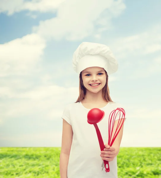 Lächelndes Mädchen mit Kochmütze mit Schöpfkelle und Schneebesen — Stockfoto