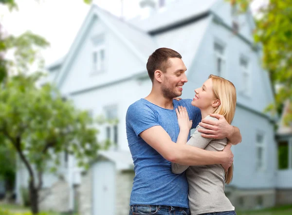 Sonriente pareja abrazando sobre casa fondo —  Fotos de Stock