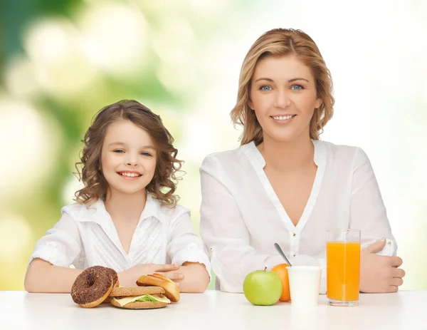 Happy mother and daughter eating breakfast — Stock Photo, Image