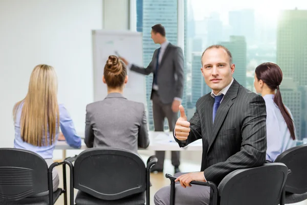 Empresario con equipo mostrando pulgares hacia arriba en la oficina — Foto de Stock