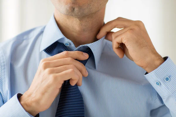 Close up de homem na camisa ajustando gravata no pescoço — Fotografia de Stock