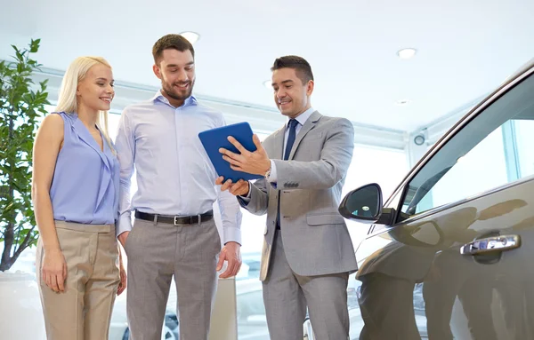 Happy couple with car dealer in auto show or salon — Stock Photo, Image