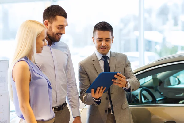 Gelukkige paar met autodealer in autoshow of salon — Stockfoto