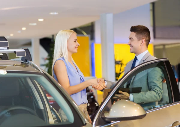 Femme heureuse avec concessionnaire automobile en salon ou salon de l'auto — Photo