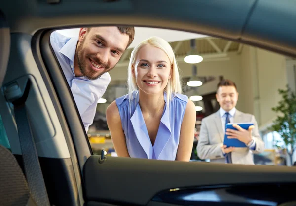 Šťastný pár s prodejci aut v autosalonu nebo salónek — Stock fotografie