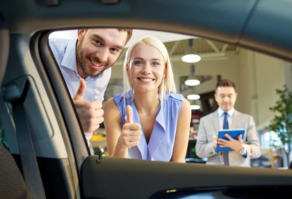 Happy couple with car dealer in auto show or salon — Stock Photo, Image