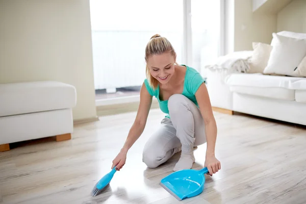 Happy woman with brush and dustpan sweeping floor — Stock Photo, Image