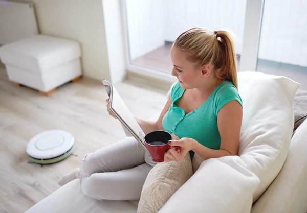 Gelukkige vrouw lezen magazine met thee beker thuis — Stockfoto