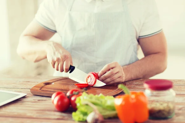 Male hand cutting tomato on board with knife — Stock Photo, Image