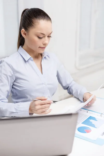 Деловая женщина с ноутбуком и графиками в офисе — стоковое фото