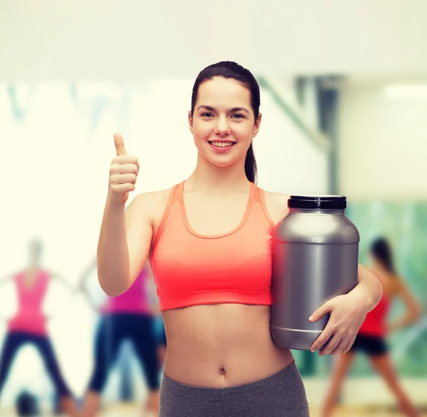 Teenage girl with jar of protein showing thumbs up — Stock Photo, Image