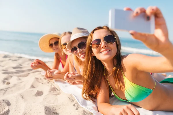 Grupo de mujeres sonrientes con teléfono inteligente en la playa — Foto de Stock