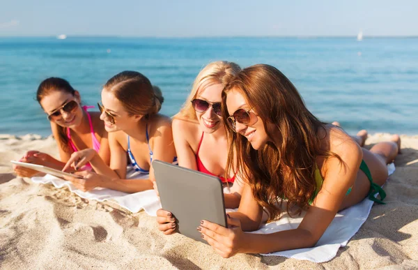 Группа улыбающихся молодых женщин с таблетками на пляже — стоковое фото