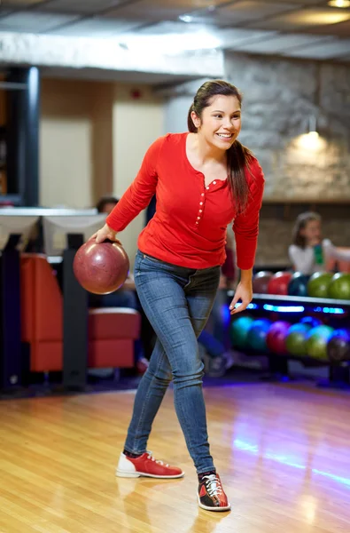 Счастливая молодая женщина бросает мяч в боулинг-клуб — стоковое фото