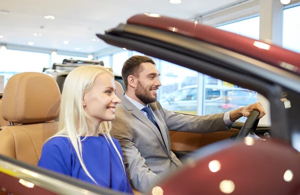 Lykkelig par som sitter i bilen i bilmessen eller salongen – stockfoto