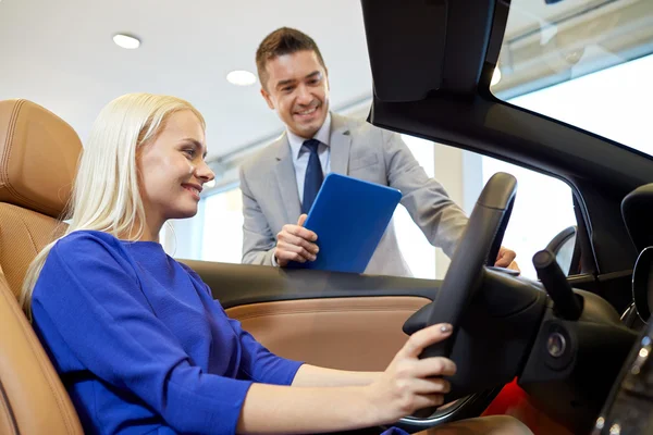 Happy woman with car dealer in auto show or salon — Stock Photo, Image