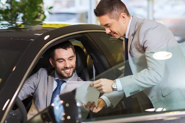 Lycklig man med Bilhandlare i auto visa eller salong — Stockfoto
