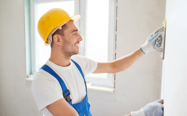 Construtor sorrindo com ferramenta de moagem dentro de casa — Fotografia de Stock