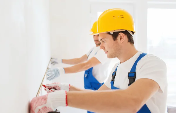 Group of builders with measuring tape indoors — Stock Photo, Image