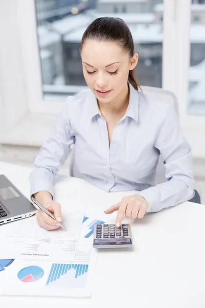 Businesswoman with laptop and charts in office — Stock Photo, Image