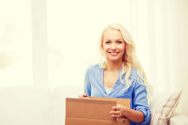 Sorrindo jovem mulher abrindo caixa de papelão — Fotografia de Stock