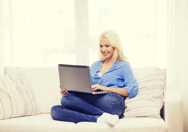 Usmívající se žena s přenosným počítačem doma — Stock fotografie