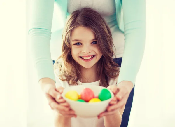 Smiling girl and mother holding colored eggs — Stock Photo, Image