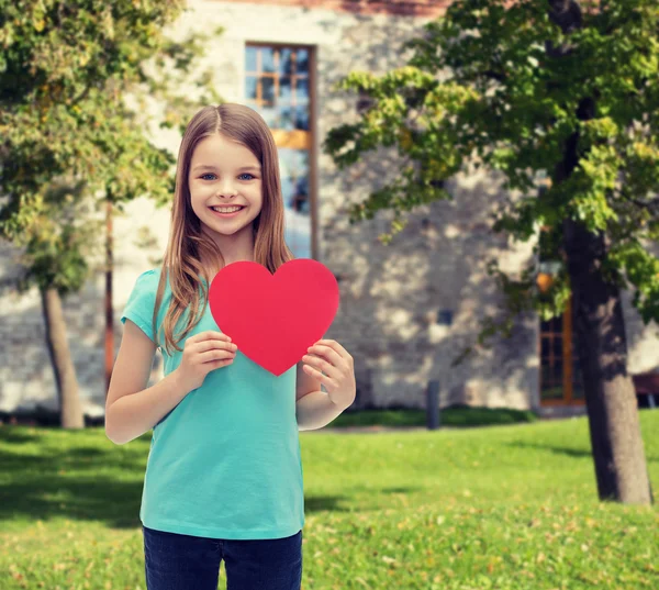 Kırmızı kalpli küçük kız gülümseyerek — Stok fotoğraf