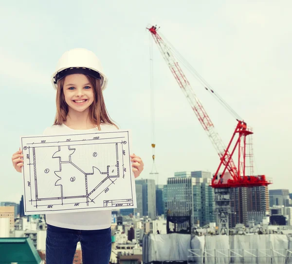 Lächelndes kleines Mädchen im Helm zeigt Blaupause — Stockfoto