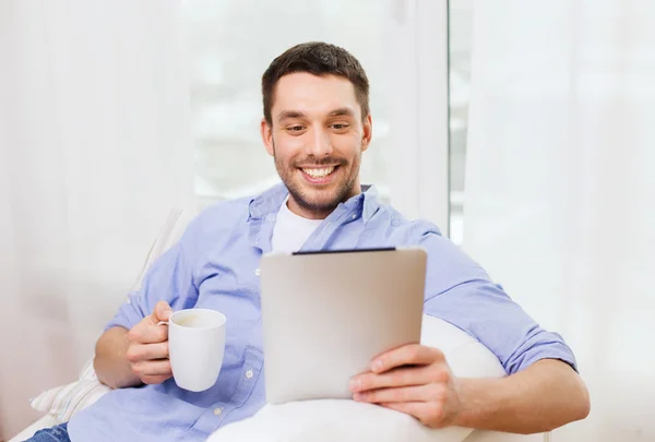 Homme souriant avec tablette pc et tasse à la maison — Photo