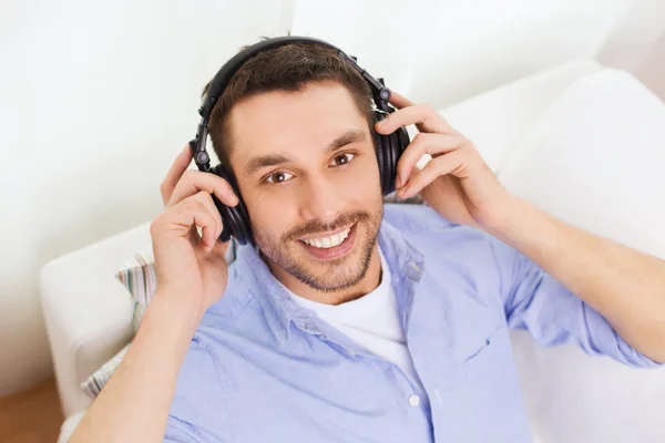 Joven sonriente con auriculares en casa — Foto de Stock