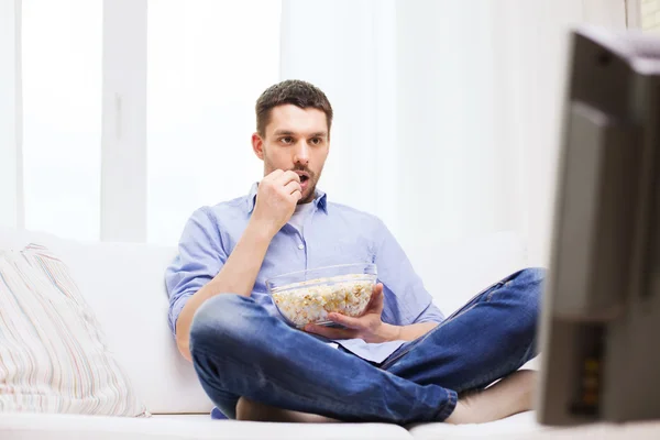 Hombre viendo la televisión y comiendo palomitas de maíz en casa — Foto de Stock