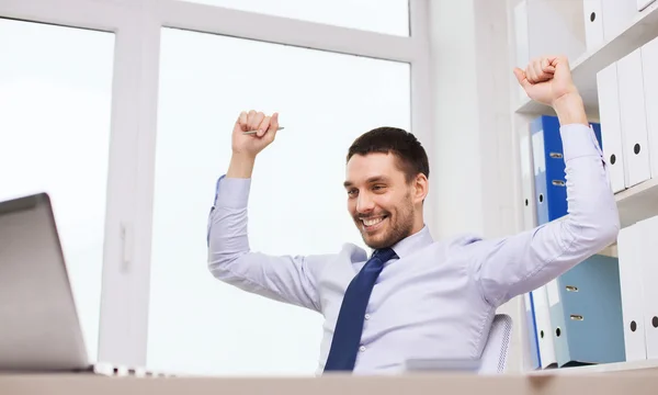 Счастливый бизнесмен с ноутбуком аплодирует в офисе — стоковое фото